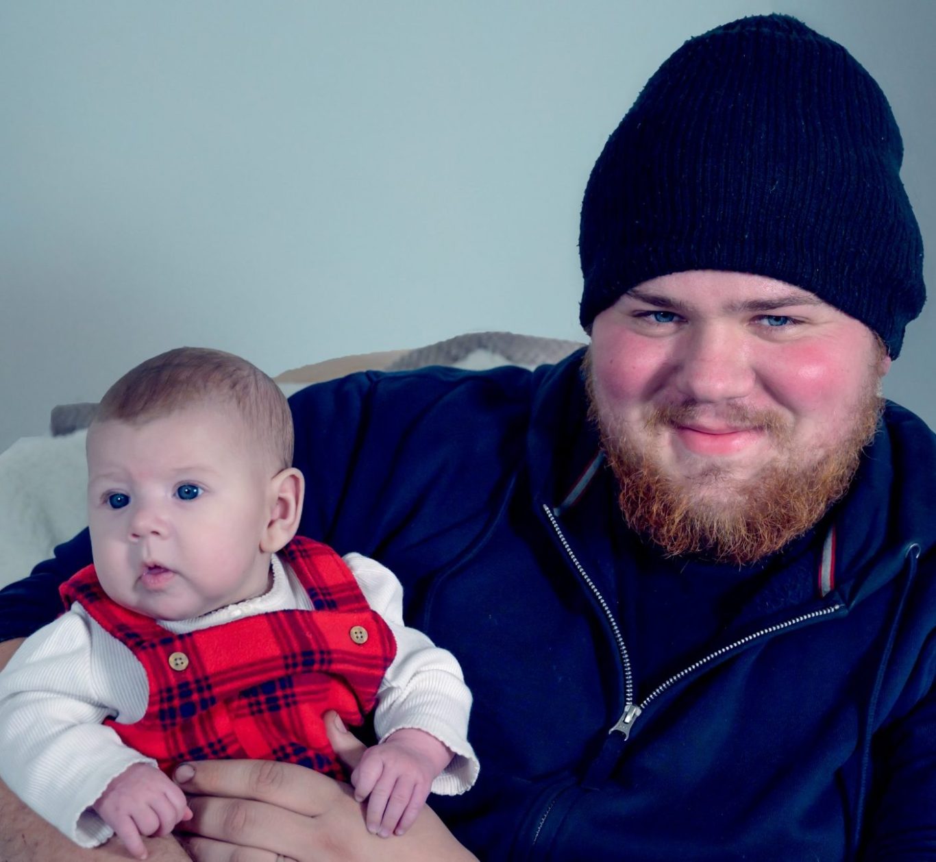 Proud farther, holding his baby girl dressed in a red tartan outfit.